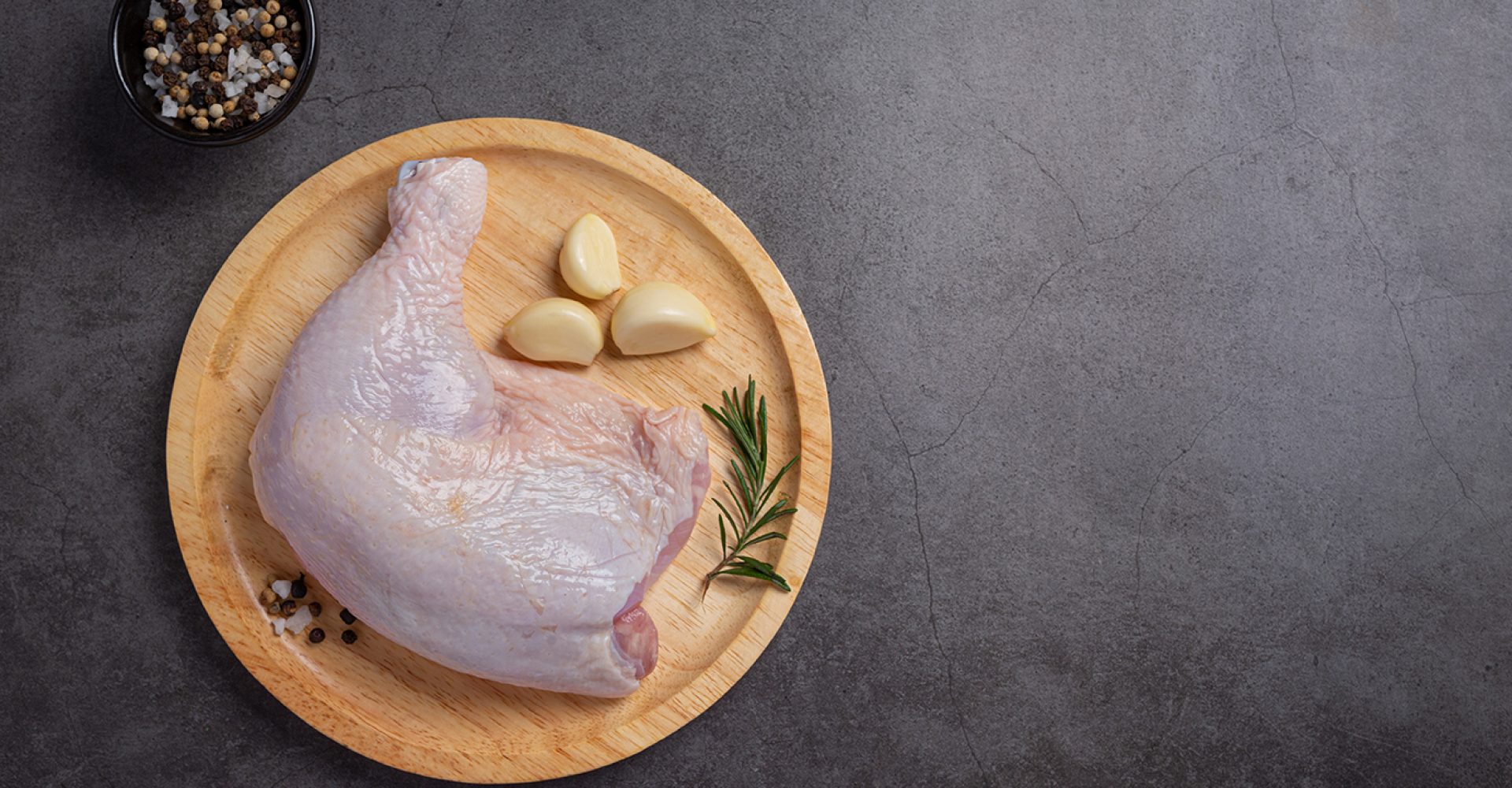 Raw chicken thighs on the dark wooden background.